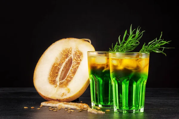 İki güzel alkollü buz, tarhun otlar ve kavun dilimleri siyah bir arka plan üzerinde bardak. Ferahlatıcı ve meyveli içecekler alkollü yaz. Taze kavun ve soğuk kokteyller. Kopya alanı.