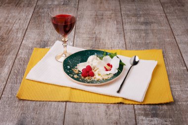 Bir güzel ve ferahlatıcı yaz tatlı. Soğuk dondurma bir orkide ile şirin çilek ve nane yaprağı. Kremsi bir tatlı ve bir bardak meyve suyu ahşap zemin üzerine sarı kumaş üzerinde.