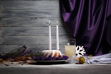 Açık gri ahşap renkli bir yeni yıl Gıda kompozisyonu. Toz şeker, meyveli içecek, tarçın ve mumlar bir tatil tablo olan bir ev yapımı vanilyalı pasta. Kopya alanı.