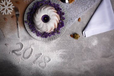 Gelen dondurulmuş tablo arka plan üzerinde şenlikli bir geleneksel Noel kek yanındaki 2018 işareti yukarıda görüntüleyin. Doğal, güzel, ev yapımı kek egzotik baharatlar ve çiçekler ile dekore edilmiştir. Kopya alanı.