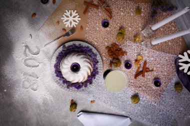 Yukarıdan görünümünü Noel yemeği bir bileşimi: badem fındık, bir bardak süt, çiçek ve kış süslemeleri yanında tarçın ile pasta. Yeni yıl 2018 işareti şenlikli bir arka plan üzerinde yazılı.