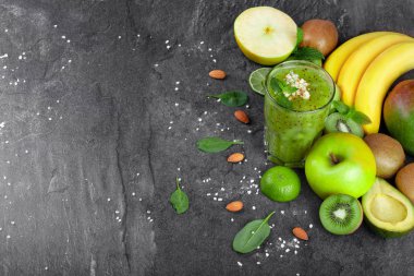 Bir gri tablosudur arka plan üzerinde yukarıdan görünüm taze sıkılmış yüzlü besleyici vitamin dolu. Muz, avokado, nane, kesme kivi ve elma masa üzerinde sağlıklı bir kompozisyon. Kopya alanı.