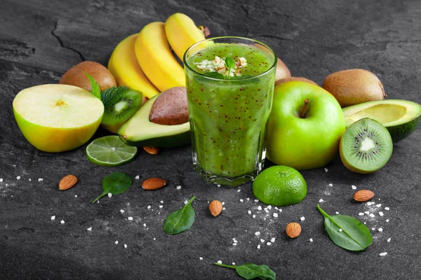 Rendelenmiş badem ve koyu gri taş zemin üzerine tropikal meyve ile taze kivi güler yüzlü bir organik bileşimi. Sarı bir dalı muz, elma, avokado ve kivi bir masada kesmek.