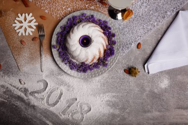 Yukarıdan görünüm geleneksel vanilya Noel kek pudra şekeri ve dekoratif çiçek çanak üzerinde gri bir arka plan etrafında serpilir. Tatil 's pasta yakınındaki bir kar tanesi. Yeni yıl 2018.