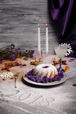 Pişmiş kek ve organik hindistan cevizi içecek gri bir arka plan üzerinde güzel bir Noel kompozisyon. Bir tatil 's Pasta krema ve çiçeklerle. Uzun mumlar, tarçın ve badem bir tablo.