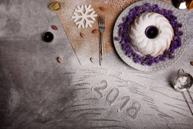 Yukarıdan görünüm geleneksel vanilya Noel kek pudra şekeri ve dekoratif çiçek çanak üzerinde gri bir arka plan etrafında serpilir. Tatil 's pasta yakınındaki bir kar tanesi. Yeni yıl 2018.