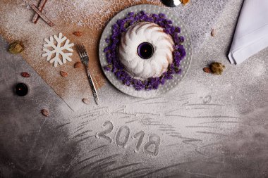 Yukarıdan görünüm geleneksel vanilya Noel kek pudra şekeri ve dekoratif çiçek çanak üzerinde gri bir arka plan etrafında serpilir. Tatil 's pasta yakınındaki bir kar tanesi. Yeni yıl 2018.