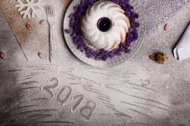 Yukarıdan görünüm geleneksel vanilya Noel kek pudra şekeri ve dekoratif çiçek çanak üzerinde gri bir arka plan etrafında serpilir. Tatil 's pasta yakınındaki bir kar tanesi. Yeni yıl 2018.