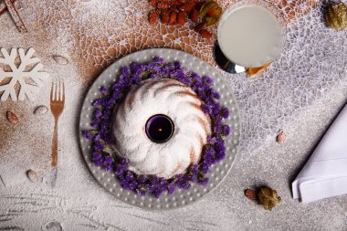 Yukarıdan bir kompozisyon bir geleneksel Noel Pasta krema ve mor çiçekler etrafında bir plaka ve renkli arka plan üzerinde pişmiş yemek. Bir Hindistan cevizi içecek ve bir yığın bir masa üzerine badem.