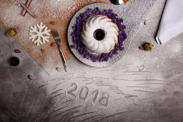 Yukarıdan görünüm geleneksel vanilya Noel kek pudra şekeri ve dekoratif çiçek çanak üzerinde gri bir arka plan etrafında serpilir. Tatil 's pasta yakınındaki bir kar tanesi. Yeni yıl 2018.