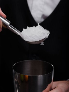 Siyah arka plan üzerine ezilmiş beyaz buz dolu bir kaşık yakın çekim resmin. Alkollü kokteyller ve smoothies karıştırma için yeni bir metal shaker bir kulüp barmen dökme soğuk buz.