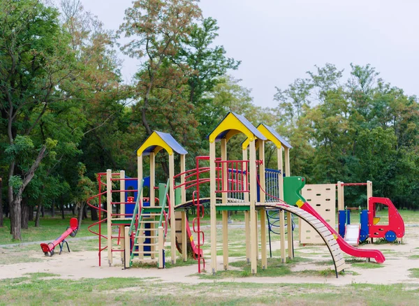 Bright playground on a natural background. A colorful playground equipment for children\'s active pastime in the park. Red slides. Outdoors, sports, childhood concept. Copy space.