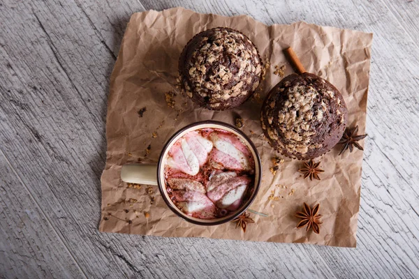 Chocolate quente com marshmallows e cupcakes em um fundo de mesa. Café e queques. Sobremesas de café de inverno . — Fotografia de Stock