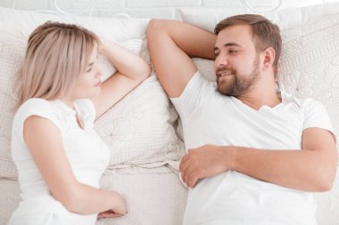 Şehvetli genç çift yatakta birlikte. Beyaz bir arka plan üzerinde izole yatak odasında mutlu çift.