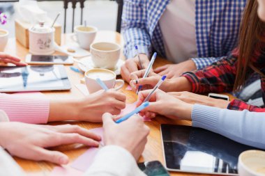 Yakın çekim öğrenciler bir tablo arka plan üzerine yazma. Kağıtları ve cihazlar ile çalışan insanlar. Proje iş kavramı.