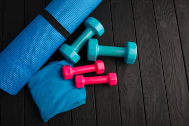 Kahverengi ahşap zemin üzerinde mavi ve pembe plastik dambıl.