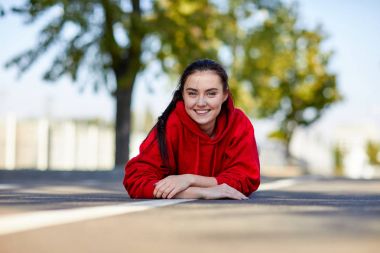 Kırmızı üniformalı bir kız yere karnına yatıyor