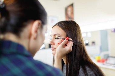 Makyöz makyaj genç bir kıza ayırıyor.