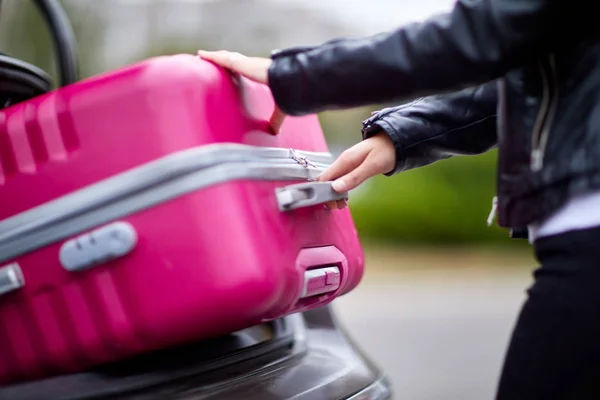 Das Mädchen nimmt einen Koffer, um ihn in den Kofferraum des Autos zu legen — Stockfoto