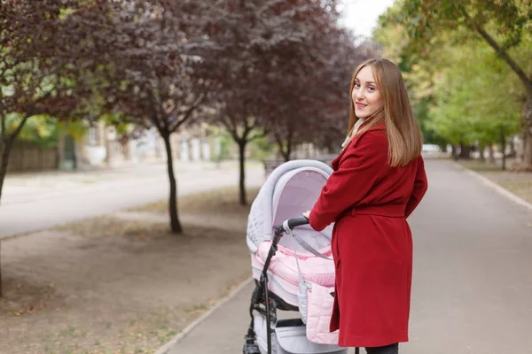 公園で赤ちゃんと一緒に歩いて若い美しいお母さん. — ストック写真