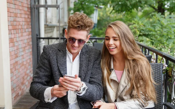 Beautiful romantic couple using a new phone on the blurred background. Internet connection concept. — Stock Photo, Image