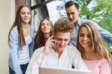 Yakışıklı adam bir telefon arıyor. Bir mobil kafe arka plan üzerinde heyecanlı gençler grup. Yeni smartphone kavramı.