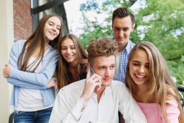 Yakışıklı adam bir telefon arıyor. Bir mobil kafe arka plan üzerinde heyecanlı gençler grup. Yeni smartphone kavramı.