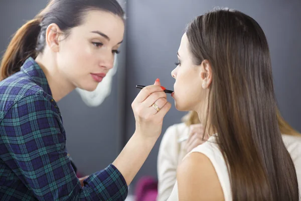 Make-up artist jest stosowania makijażu do młodej dziewczyny. — Zdjęcie stockowe