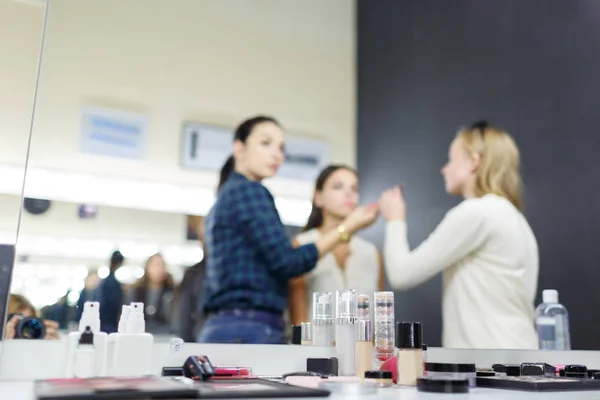 Um maquiador está aplicando maquiagem a uma jovem . — Fotografia de Stock