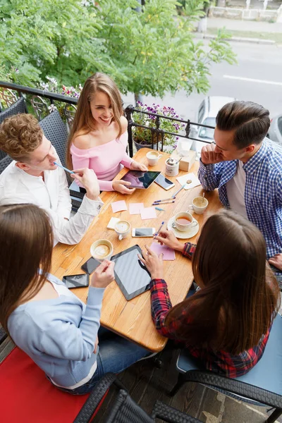 Tabletler ve telefonları, bulanık bir arka plan üzerinde rahatlatıcı ile gülümseyen arkadaş grubu. Öğrenci hayat kavramı.