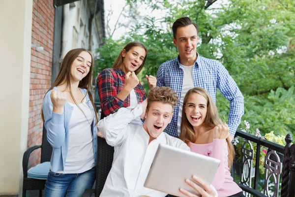 Group of teens using tablet on a cafe background. Happy friends with tablet. Modern lifestyle concept. — Stock Photo, Image