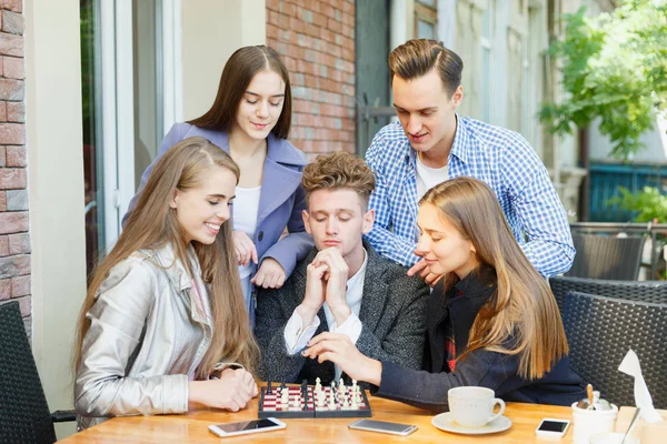 Друзі-підлітки грають у шахи і думають на фоні кафе. Концепція гри в шахи . — стокове фото