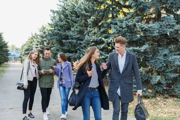 Pareja joven caminando con amigos. El tipo sostiene a las chicas de la mano . — Foto de Stock
