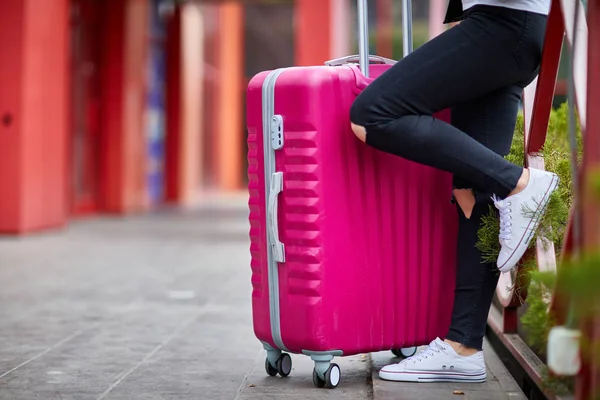 Ein Mädchen steht mit einem pinkfarbenen Koffer am Geländer — Stockfoto