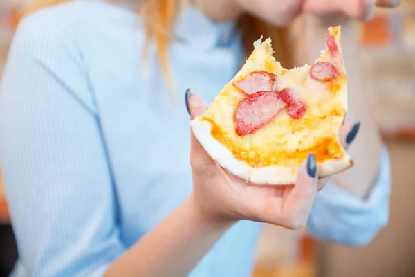 Smiling office lady, at lunchtime and eating pizza. Festive atmosphere.