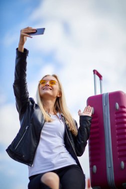 Bir kız selfie pembe bir bavul bir arka plan üzerinde yapar.