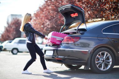 Kız pembe bavulu bagajdan dışarı alır