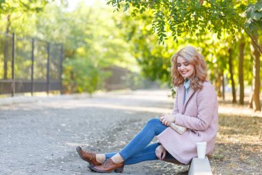 Güzel sarışın Kaldırıma park kahve ile oturuyor.