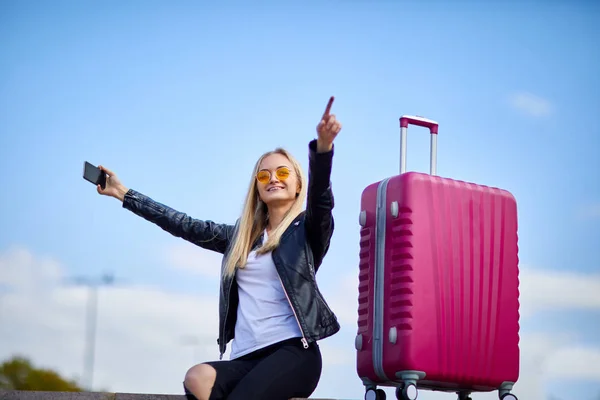 Ein Mädchen macht ein Selfie auf dem Hintergrund eines rosa Koffers — Stockfoto