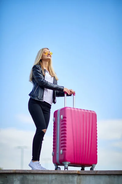 Mädchen mit einem rosa Koffer auf einem Hintergrund von einem schönen blauen Himmel — Stockfoto