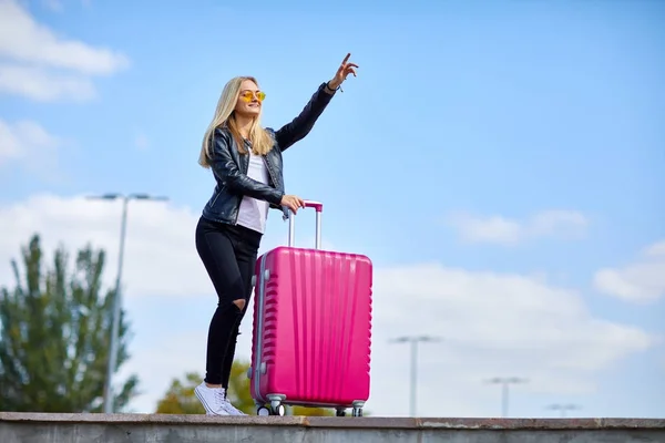 Mädchen mit einem rosa Koffer auf einem Hintergrund von einem schönen blauen Himmel — Stockfoto