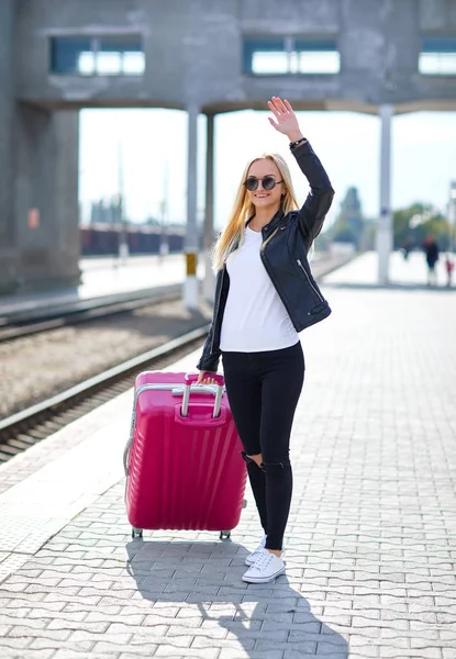 Ein Mädchen mit rosa Koffer steht am Bahnhof — Stockfoto