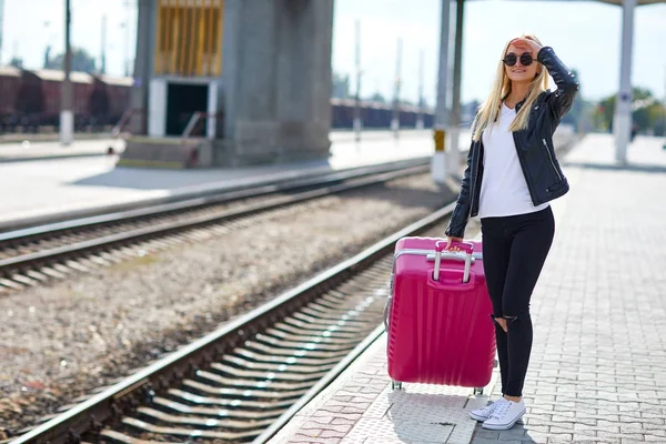 Ein Mädchen mit rosa Koffer steht am Bahnhof — Stockfoto