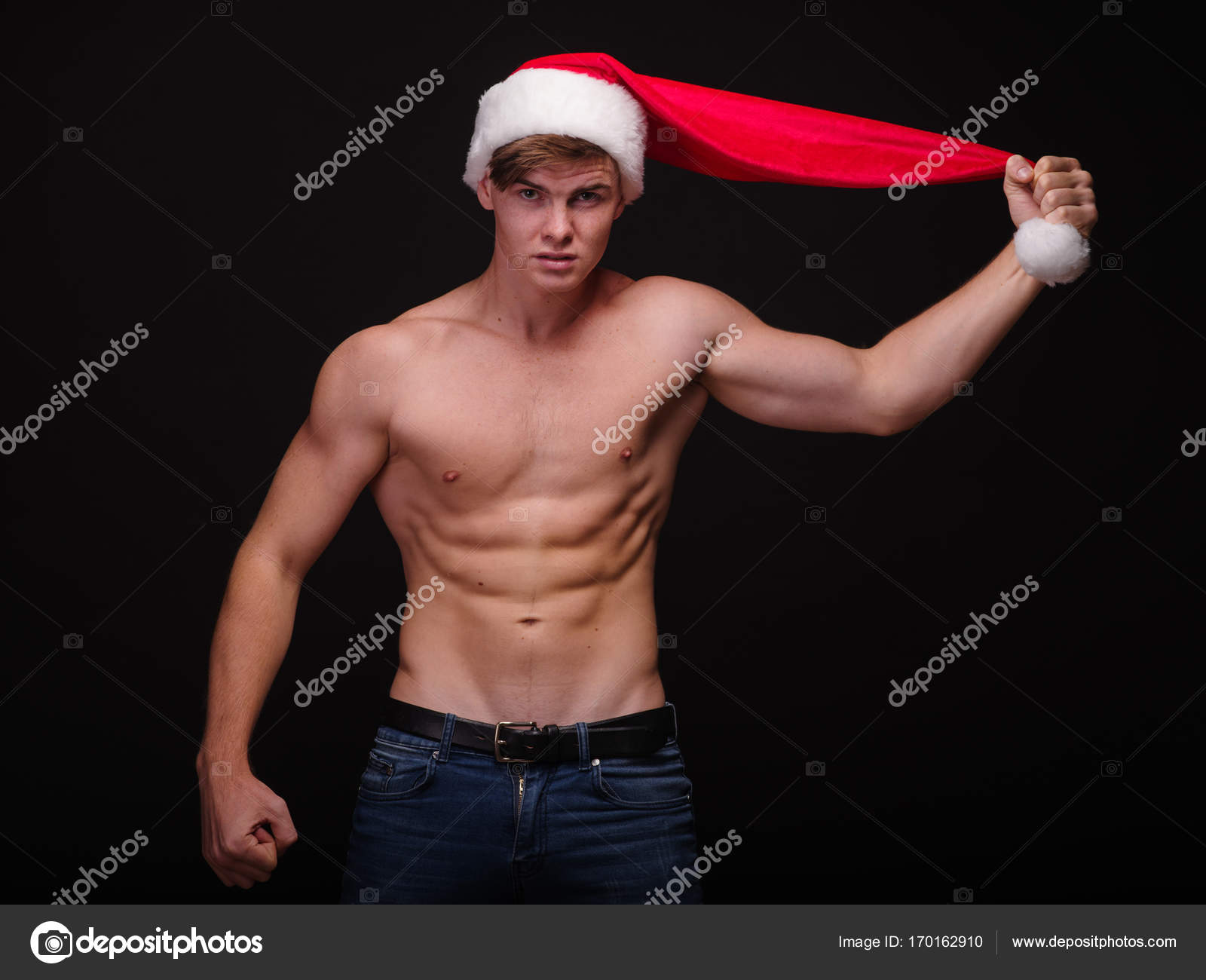 Père Noël torse nu dans un chapeau rouge sur un fond noir. Beau garçon de Noël. Concept de fête