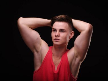 Seksi kaslar üzerinde siyah bir arka plan ile güzel, atletik bir adam. Gençlik güven kavramı.