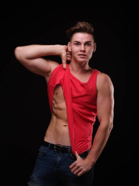 Seksi kaslar üzerinde siyah bir arka plan ile güzel, atletik bir adam. Gençlik güven kavramı.