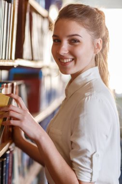 Bir kitap bir raf kütüphanede alarak bir öğrenci.