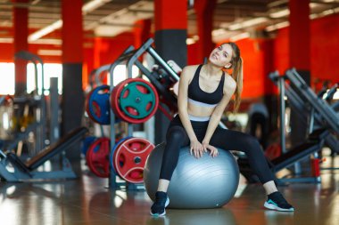 Fitness Ball modern salonda oturan genç kız.
