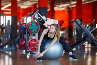 Fitness Ball modern salonda oturan genç kız.