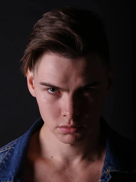 Close-up menino adolescente bonito em um casaco de jeans em um fundo preto. Corte de cabelo masculino e conceito de estilo . — Fotografia de Stock